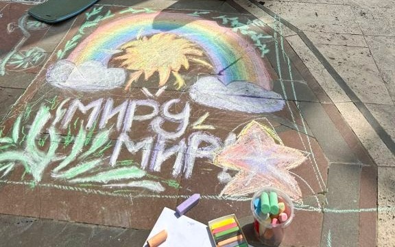 Рисунок мелом на асфальте: радуга, солнце и надпись «Миру мир!»